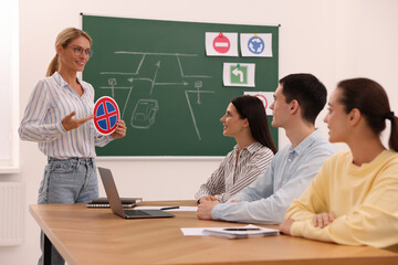 Teacher showing No Stopping road sign to audience in driving school