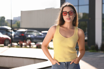 Beautiful woman in sunglasses on city street, space for text
