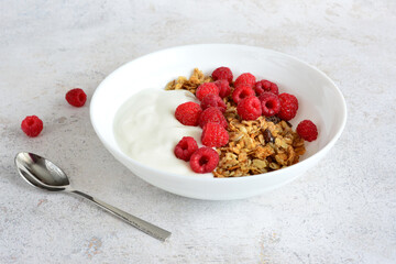 granola with raspberry and yogurt in white bowl 