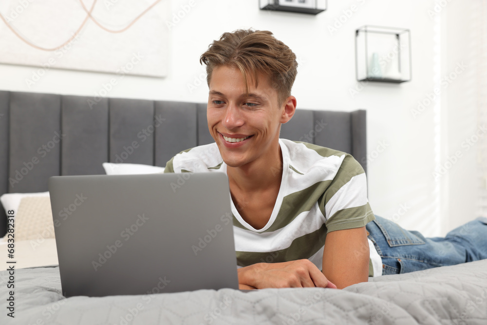 Sticker Happy young man having video chat via laptop on bed indoors