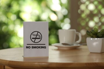 No Smoking sign on wooden table against blurred background