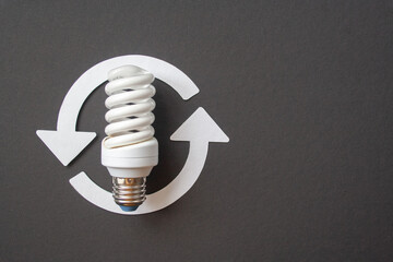 Energy saving light bulb and recycle arrows. Economical consumption of electricity. Black background . The concept of nature conservation and renewable energy sources