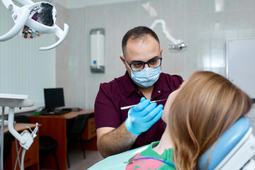 A young Dentist treating a female Patient in the dental studio