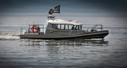 Modern pirates on a motor boat in a bay under a pirate flag