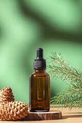 Cosmetic bottle between fir branches and pine cones. Skin care cosmetic. Hyaluronic acid oil, serum with collagen and peptides. Natural cosmetics.