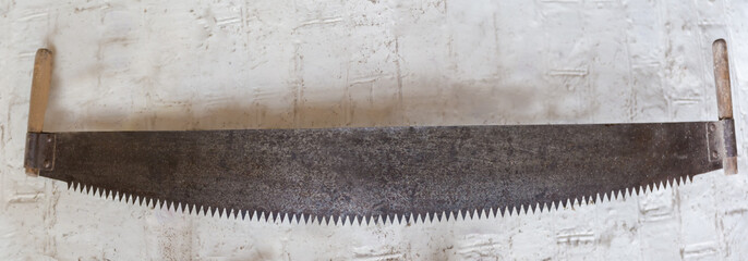 Old two-man crosscut saw against the white wall