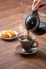 湯気の出る温かいコーヒーとスコーン、ホットコーヒーを注ぐ