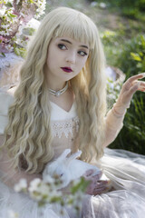 Naklejka premium The beautiful girl with white rabbit in the blossoming apple-trees garden. White flowers in a garden in sunshine. Spring apple trees in blossom. Beautiful woman among spring blossom