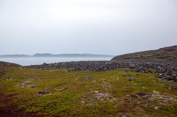 A cluster of stone boulders on the shores of the Barents Sea. Rural settlement Teriberka. Kola...