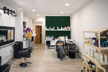 General view of hairdressing salon. Professional hairdresser with purple hair. Washing the head of...
