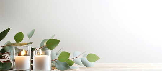 Glass and candles arranged on a white table with eucalyptus