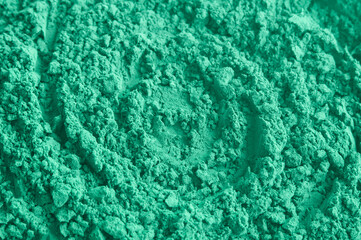 Green bentonite facial clay powder (alginate mask, eye shadow) texture close up, selective focus. Abstract background.