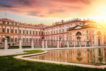 View of a portion of the Villa Reale of Monza reflected in the fountain in front at sunset with the glow of the sun
