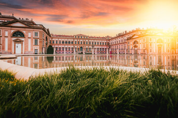 View from below of the Villa Reale in Monza reflected in the fountain in front at sunset with sunlight glow
