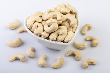 A top view of whole cashew nuts arranged beautifully in a heart-shaped bowl against a clean white background