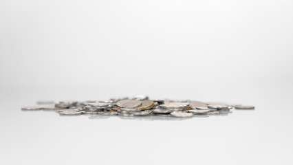 pile of coins that have a mixed value with the currency being baht Close-up focus on coins and blurred in the distance. The background is white, suitable for use as an illustration of writing.