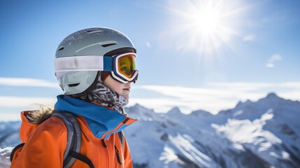 A girl child in ski goggles and equipment looks to the side against the backdrop of a sunny winter mountain landscape