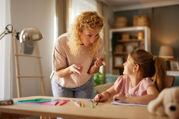 Mother scolding her daughter while helping her with homework at home