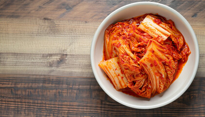 Kimchi cabbage in a bowl on wooden background, top view, Korean food