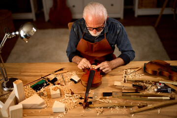 Senior violinmaker making violin instrument
