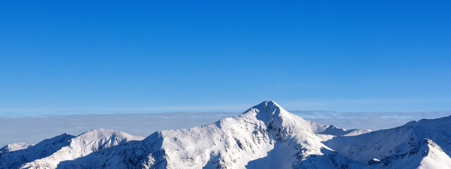 Obraz premium Banner chain of snow-capped mountain peaks against a blue sky in Slovenia