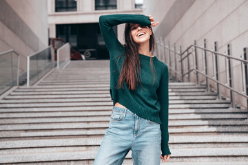 Street fashion portrait of beautiful caucasian woman walking outdoors. Beautiful young model in warm sweater. Fashion stylish pretty female posing in the street, having fun in city