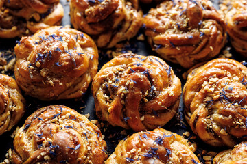 Sweet cardamom rolls sprinkled with chopped nuts and dried cornflower petals,  focus on the bun inside. Homemade sweet baked goods