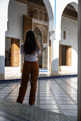 (Selective focus) Stunning view of a tourist taking a photo at the Bahia Palace during a sunny day. The Bahia Palace in Marrakech is an impressive example of Moroccan architecture and design.