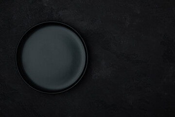 Empty plate. Dark black ceramic empty plate on dark black stone background.