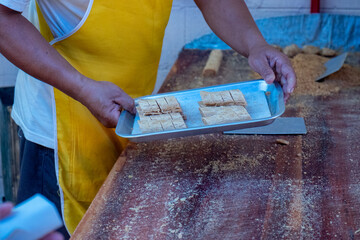 Chef Hold a Tray of  Horizontal Stacks of Smashed Caramelized Peanut Candy