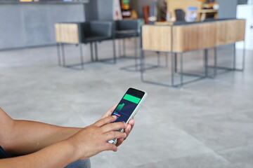 Hand of Mature Adult trader investor analyst holding smartphone looking at app analytics Stock exchange trading data. Businessman uses his right hand to tap the phone screen to buy or sell stocks. 
