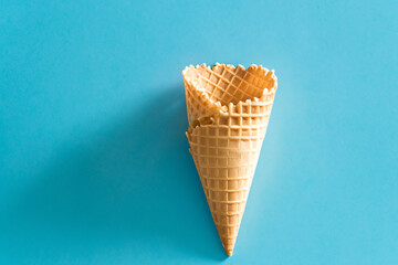 The image shows a single ice cream cone placed on a blue background. The minimalist composition and...
