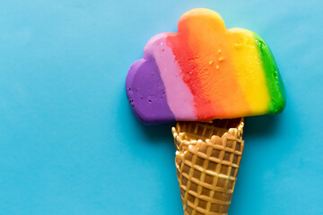 The image depicts a colorful ice cream cone with rainbow-colored scoops of ice cream, nestled in a...
