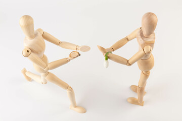 Wooden puppet holds a gold ring with a diamond. Marriage proposal.