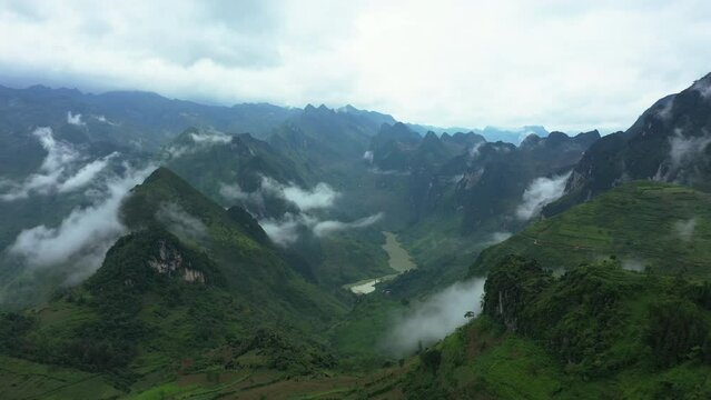 Drone of green mountain top, clouds and nature for travel background, tourism location and holiday adventure. Aerial view of landscape, river and forest for eco vacation in Vietnam, Ma Pi Leng Pass