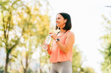 Beautiful fit woman keeps herself hydrate before and after sport outdoors in the morning.