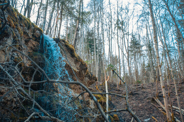 A peaceful autumn forest reflected in a peaceful flowing river. A serene waterfall in a lush autumn forest surrounded by rocks.