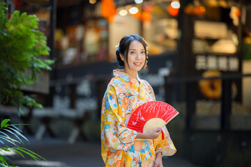 Asian woman try to wear Japanese kimono with the traditional Japanese village background