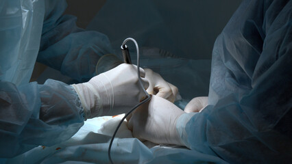 Skilled surgeons in white gloves performing manipulations with patient body at bright light....