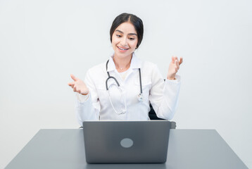 Young Indian doctor in traditional medical clothing consulting with patient online using tablet computer. The doctor is sitting at a desk and talking to the patient.