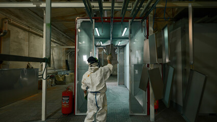 Worker pushing line of painted metal sheets into the drying chamber. Creative. Steel production...