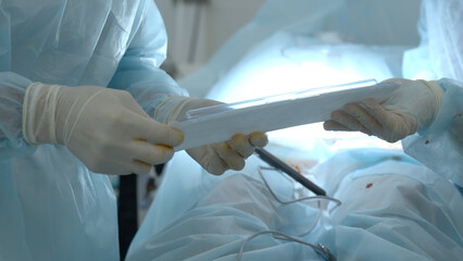 Nurse passing disposable sterile kit to a doctor in operating room. Action. Concept of healthcare and medicine.