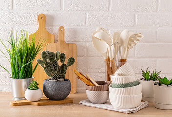 Light kitchen background with wooden eco-friendly kitchen utensils. different green potted plants....