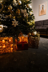 A New Year tree decorated with toys and gifts stands in the room. Christmas and New Year concept