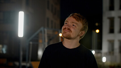 Portrait of a happy handsome man looking around in a dark street. Media. Male model posing on...