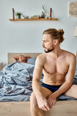 upset bearded man in underpants sitting on bed near sleeping love partner, troubled relationship