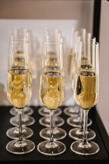 Champagne flutes in holiday. Champagne glasses in restaurant. Glasses are filled with champaign. Celebration of the Happy New Year 2024, Christmas holidays, birthday party, wedding and baptism.