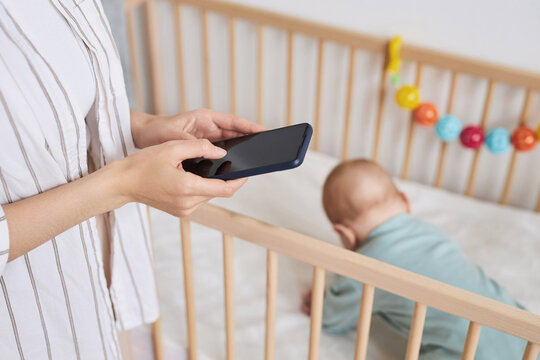 Close Up Of Unrecognizable Mother Holding Smartphone With Blank Screen While Caring For Baby Boy And Researching Childcare, Copy Space