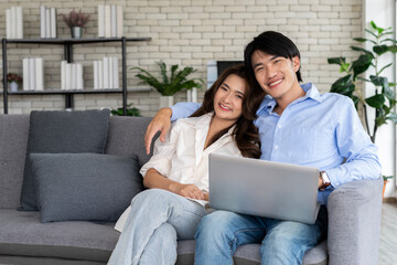 Young couple planning future together on couch with Laptop internet