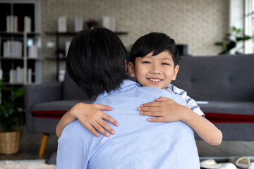 Happy asian father hugging little son at home in living room.